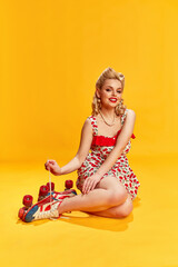 Portrait of beautiful young girl with stylish hairstyle in dress, on vintage rollers posing against...