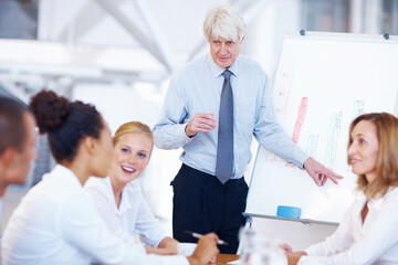 Successful business man presenting to his team. Portrait of successful senior business man presenting to his colleagues.