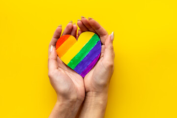 Female hands with rainbow LGBT colored heart paper cut. LGBT social rights concept.