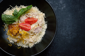 pasta carbonara with bacon, tomatoes and cheese, on a dark background