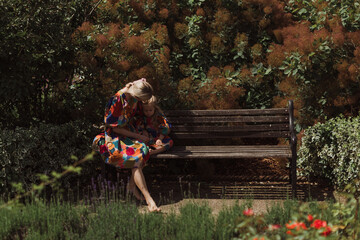 Young mother siting with her little daughter in the rose garden. Portrait mom with child together on nature. Mum, little daughter outdoors. Happy Mothers Day..