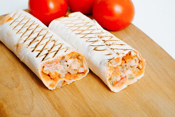 Sliced cooked shawarma on wooden board with ingredients tomato stuffing chicken doner fast food