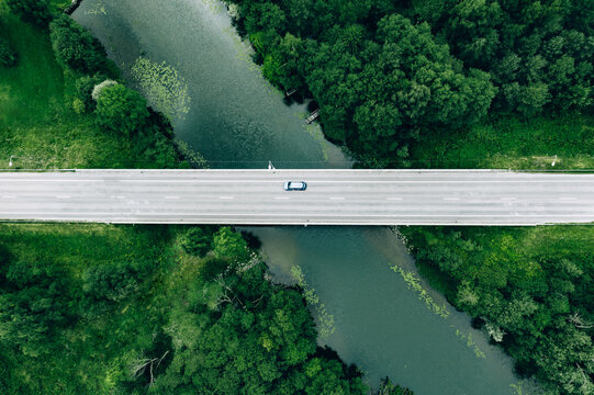 Aerial View Of Road With Blue Car Over The River And Green Woods In Finland