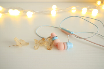 pastel pink and blue earphone on white table with dry flowers