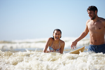 Always the right time to try something new. a laughing young woman being given a surfing lesson.