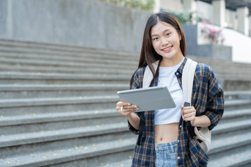 A pretty smiling Asian female student holding a tablet to collect data in a biology paper at university.