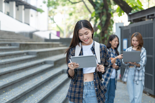 A pretty smiling Asian female student holding a tablet to collect data in a biology paper at university.