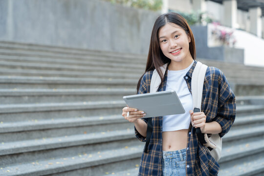 A pretty smiling Asian female student holding a tablet to collect data in a biology paper at university.