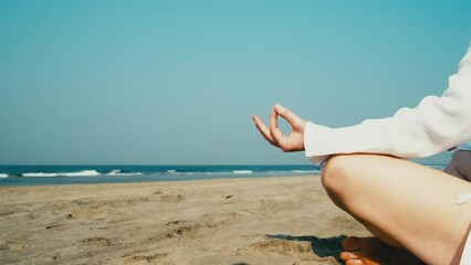 Close-up hand of woman doing meditation exercises on the beach. Female mindful practice on the desert seashore.