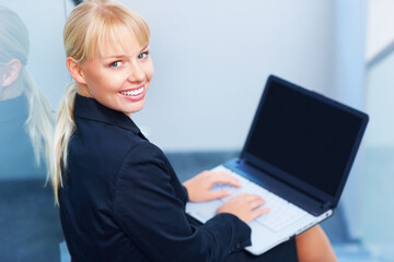 Business woman using laptop on stairs. Business woman smiling and working on laptop while sitting on staircase.