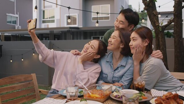Young adult asia people hug love care for mom taking photo selfie video on mobile phone camera at home picnic dining fun night party dine table. Relax older mum smile enjoy warm time happy hour meal.