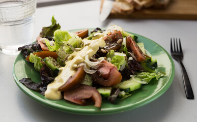 vegetable salad of greens, tomatoes and cucumbers on a green plate