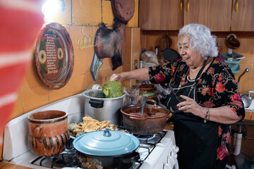 A senior mexican woman is smiling while preparing chayote to go with battered poblano chiles