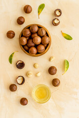 Bowl of of macadamia nuts oil with raw nuts. Natural oil for cosmetic or cooking