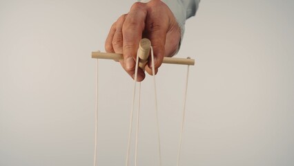 The puppeteer's hand controls the puppet with a wooden manipulator and strings. The marionettist...