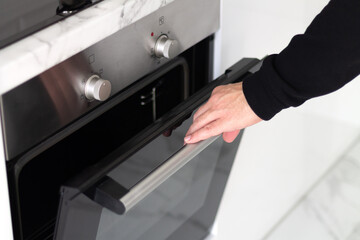 Man open modern electric oven, making dinner at home concept