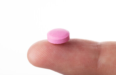 The pill on the finger extra close up. The pink pill extra macro view.
