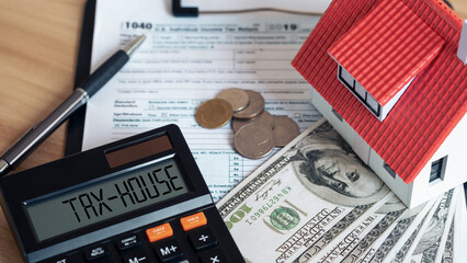 Tax house on calculator and Miniature house with money on tax papers. The concept of paying tax for...