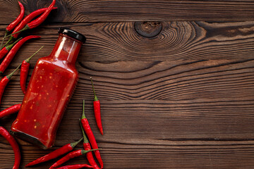 Red chili pepper sauce in bottle with ripe hot pepper