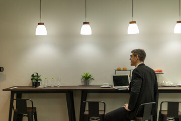Young business man uses computer notebook to work with his colleagues at a café counter. Male officer works with his laptop in a coworking space.
