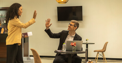 Two travelers greet each other by high five in an exclusive lounge at the airport before departure