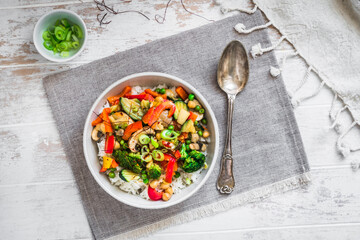 Bowl with rice and vegetables on white wooden table, vegetarian, vegan, healthy food, top view