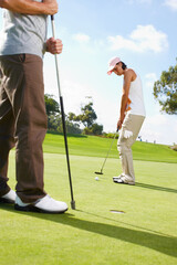 Obraz premium She doesnt let anything distract her. Young woman putting on the golf course with her husband in the background.