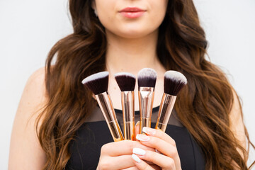 Woman holding makeup brushes in hands. 