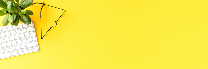 Office desktop with computer keyboard and eyeglasses. Top view