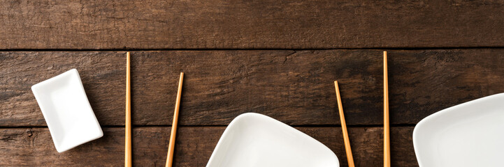 Empty sushi plates with chopsticks on wooden table. Top view