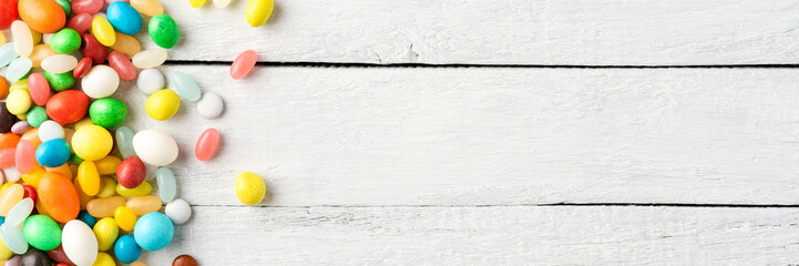 Various kinds of colourful sweets on white wooden table. Top view