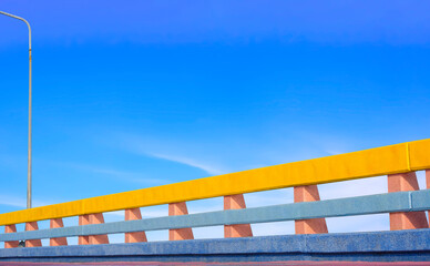 Row of colorful Bridge railing and sidewalk with street lamp post against blue sky background at sea viewpoint, low angle view with copy space