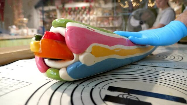 Close-up of a pastry chef rolling out multicolored caramel on a table in a professional pastry shop. Creation of handmade sugar candies.
