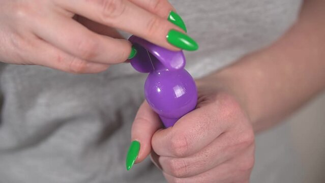 a girl in a gray t-shirt touches a purple sex toy with her hands. close-up. slow motion video. High quality Full HD video recording