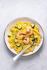 Pasta Mafalde or  Garganelli with courgettes, shrimps and saffron. A creamy delicious Italian recipe with seafood and vegetables, a delicious flavor combination. Grey stone background, top view
