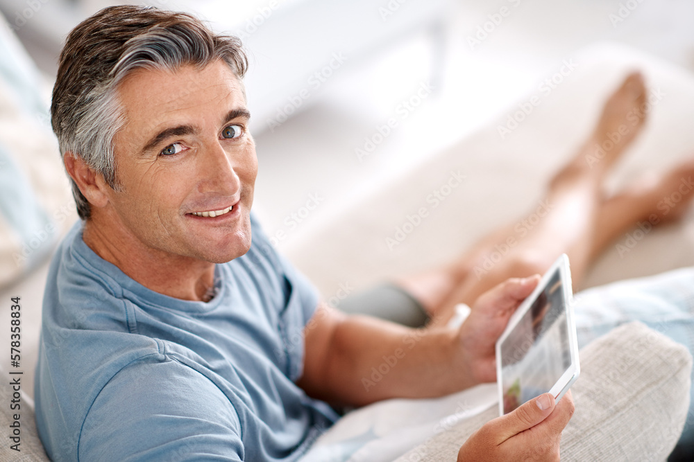 Poster sitting back and relaxing. cropped portrait of a handsome mature man using a tablet while sitting on