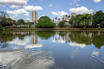 Fototapeta na wymiar Uma paisagem de um dos lagos do Bosque dos Buritis na cidade de Goiânia. O lago com árvores e céu azul com algumas nuvens.