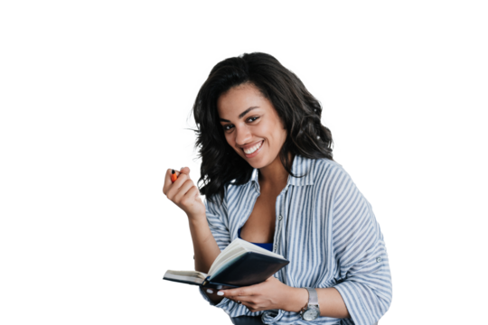 Cheerful African American girl in casual clothes holds diary and pen using laptop looks at camera planning agenda. Happy Brazilian young woman remote works against transparent background. Student