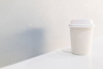 Takeaway white coffee cup on on gray wall with copy space for text