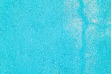 Rough concrete wall painted in blue color with cracked line and faded white