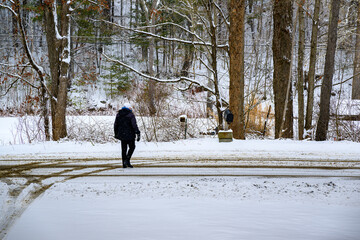 During the winter in Windsor in Upstate NY you need to put on your hat, coat, boots, and gloves to walk to the mailbox.  Road plowed and the mail has come.  Woman walks to mailbox.