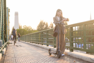 Portrait of young business woman with an electric scooter to work over bridge in modern city  background © tonefotografia