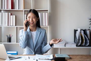 Young beautiful businesswoman having a phone call with her customer in the office room.