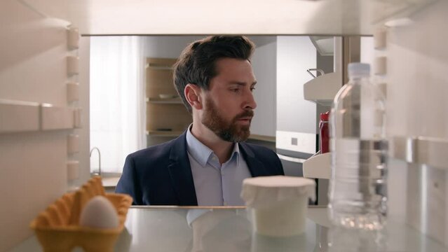 Point of view POV inside refrigerator Caucasian businessman employer man open fridge empty shelves with one egg and bottle of water order food with mobile delivery service buying products with phone