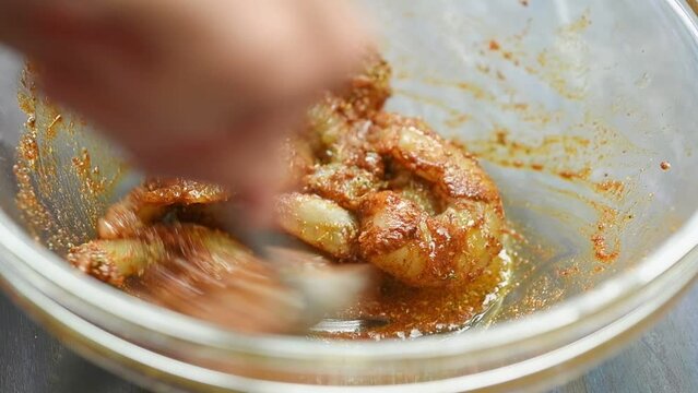 The chef stirs shrimps with spices into the bowl.
