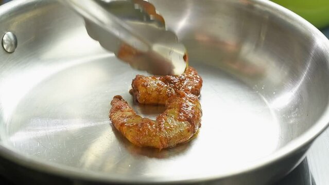 The cook puts shrimps in the frying pan.

