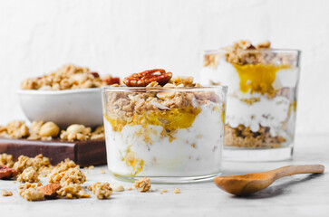 Granola and Yogurt Parfaits, Healthy Breakfast or Snack, Muesli with Nut Mix and Honey on Bright Concrete Background