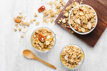 Granola and Yogurt Parfaits, Healthy Breakfast or Snack, Muesli with Nut Mix and Honey on Bright Concrete Background