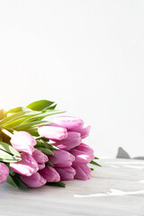 Pale pink delicate tulips on a white wooden background. Spring background with a bouquet of flowers. Front view