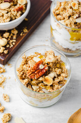Granola and Yogurt Parfaits, Healthy Breakfast or Snack, Muesli with Nut Mix and Honey on Bright Concrete Background